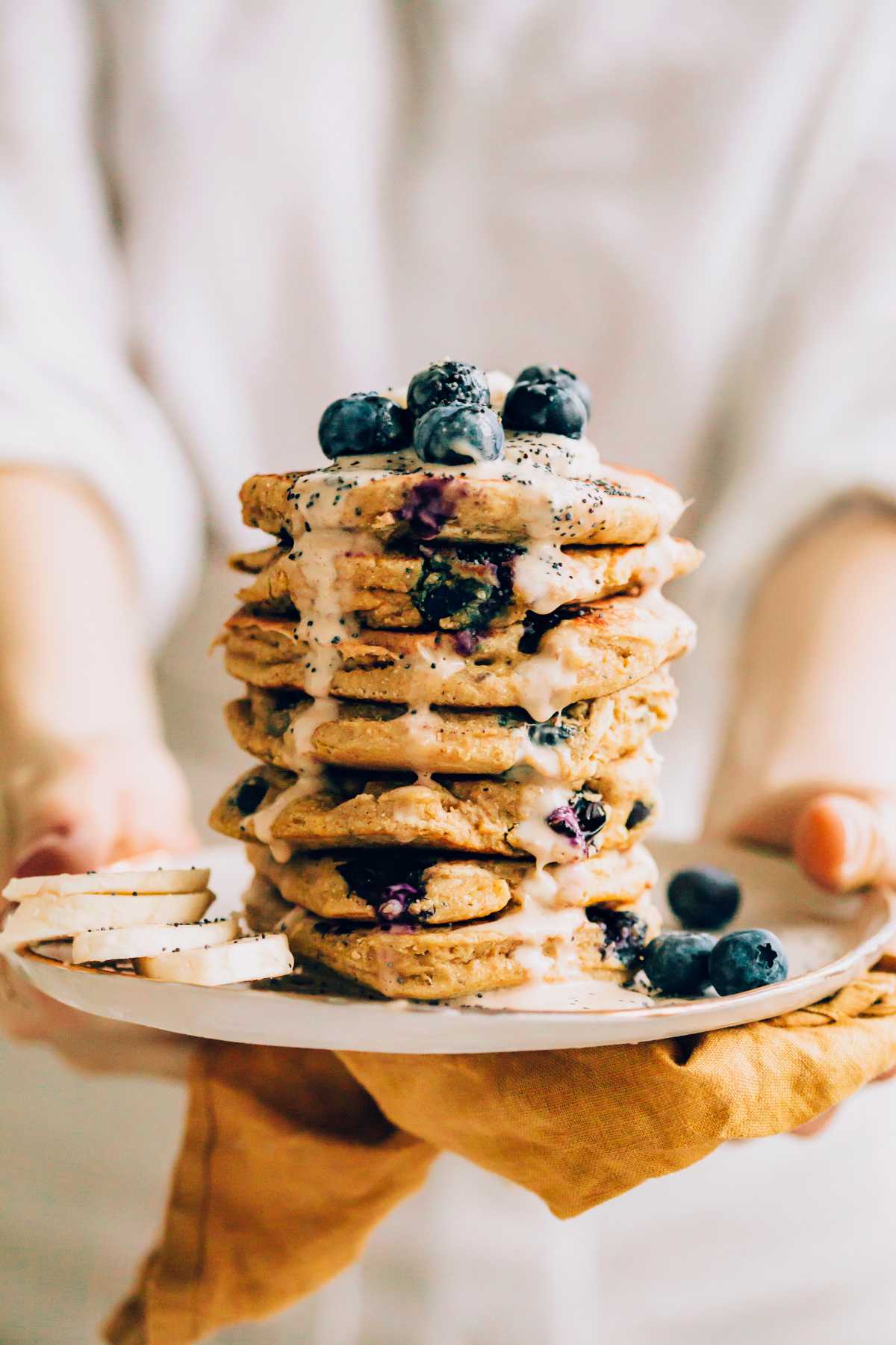 woman holding a plate of vegan oatmeal pancakes