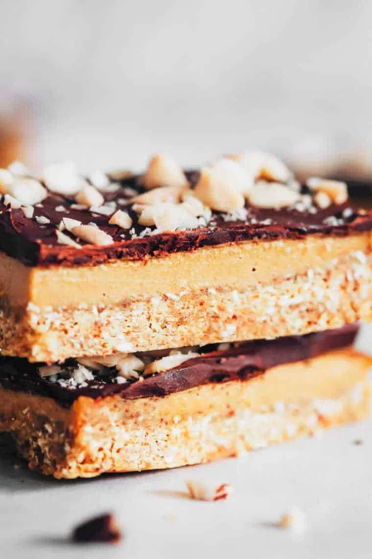 white table with two homemade raw vegan caramel slices on top of each other