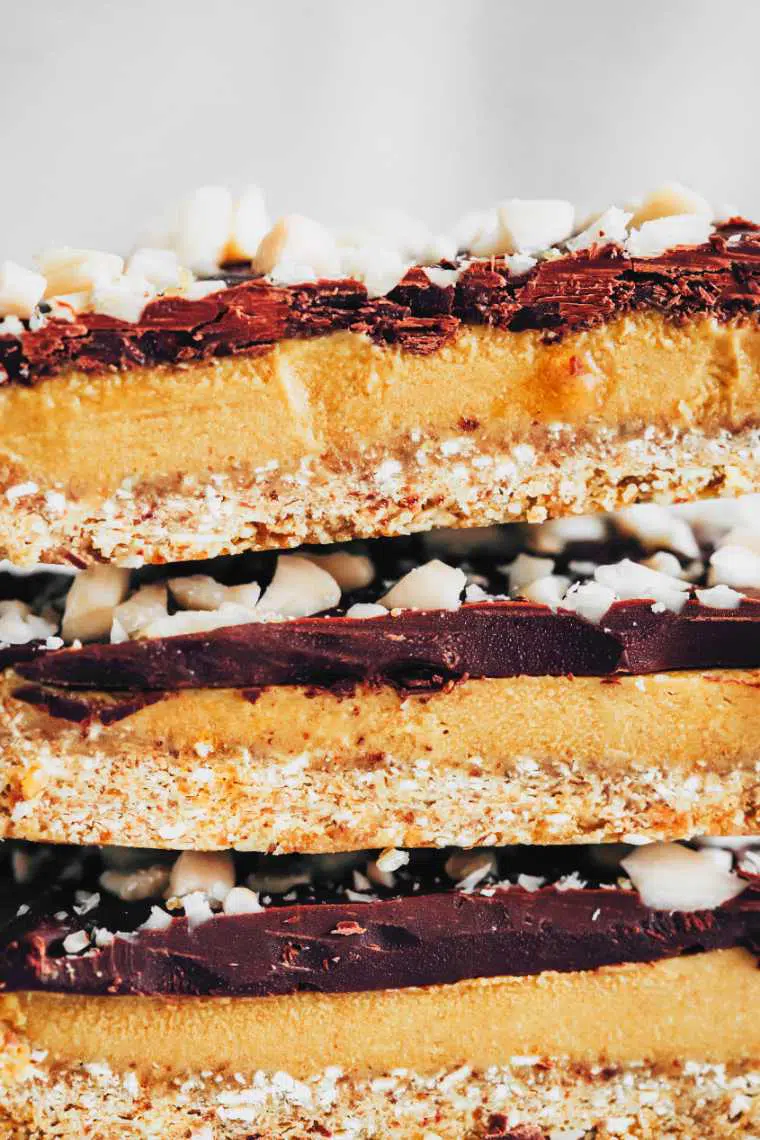 three no-bake vegan caramel slices topped with chopped almonds on top of each other