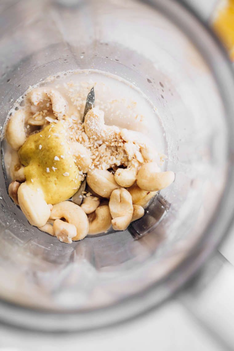 top view of a blender jar containing cashews, mustard, water and nutritional yeast