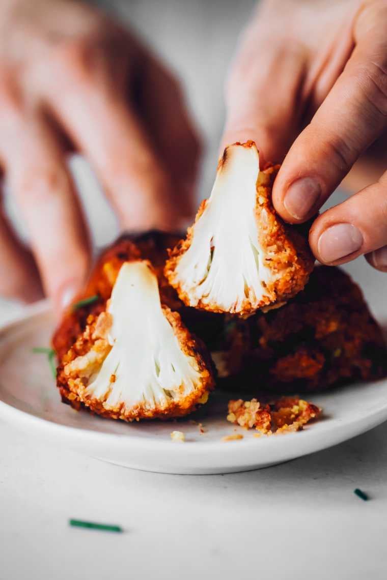 vegan cauliflower buffalo bite cut open and a hand showing the texture on the inside