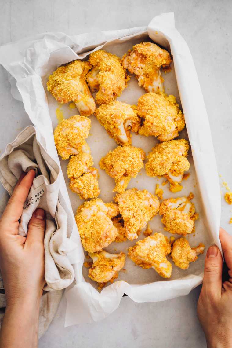 uncooked vegan cauliflower buffalo wings on a baking dish with parchment paper