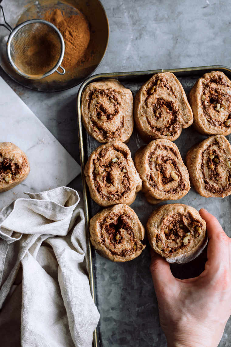 woman placing raw cinnamon rolls next to each other in a baking dish