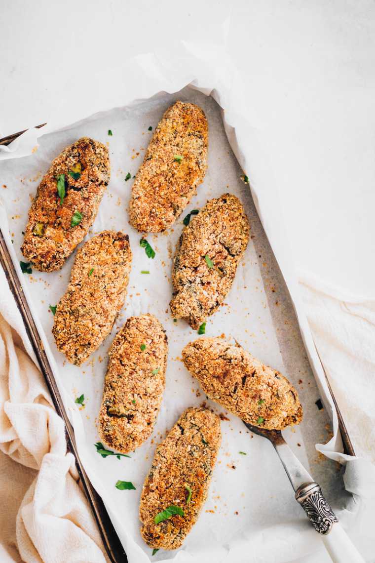 baking tray with parchment paper and 7 freshly baked vegan vegetable croquettes