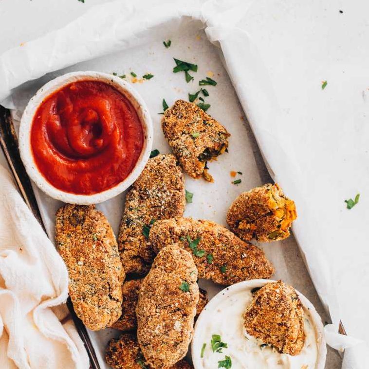 baking tray with seven vegan potato croquettes, ketchup and vegan french onion dip