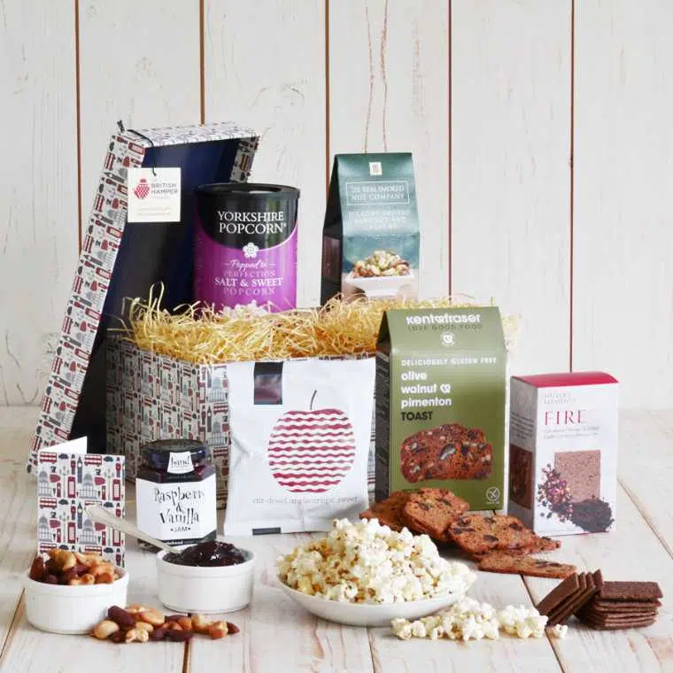 wooden table with a lovely box filled with jam, crackers, popcorn, nuts and more
