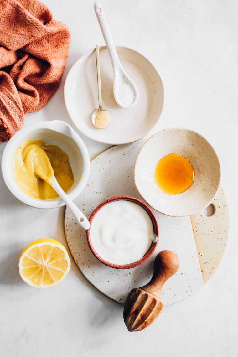 table with four bowls containing mustard, maple syrup, vegan yogurt and spices