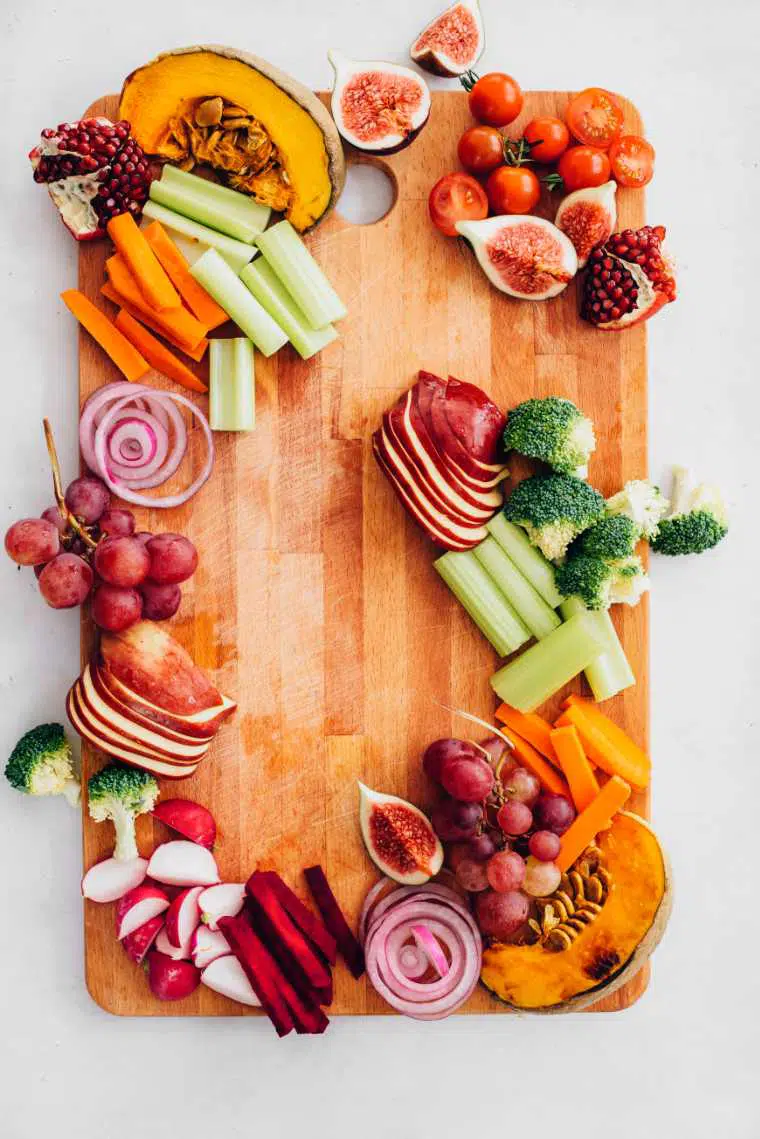 wooden appetizer platter with raw veggies, figs, pomegranate, grapes and roast pumpkin