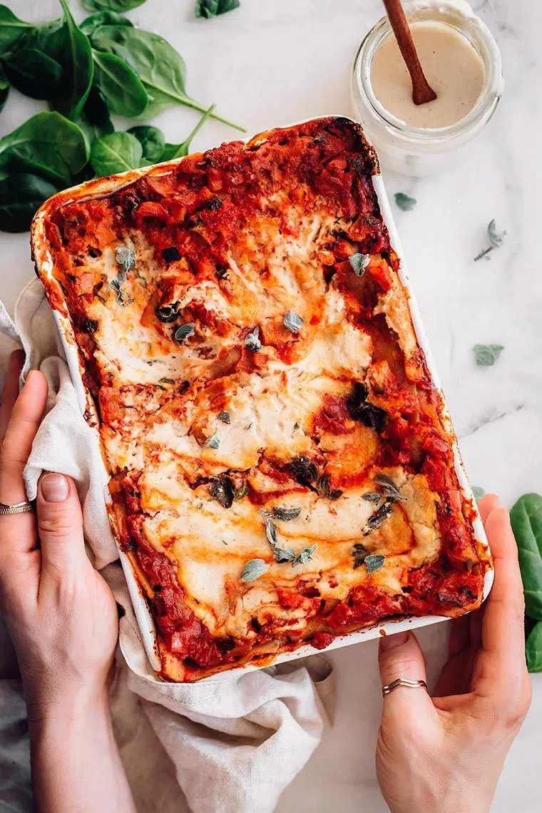 white baking dish on a table filled with red and white dairy-free baked lasagna