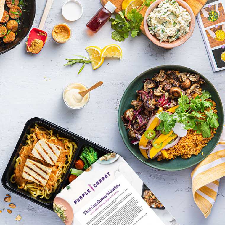 table with bowls of vegan food next to a package by Purple Carrot