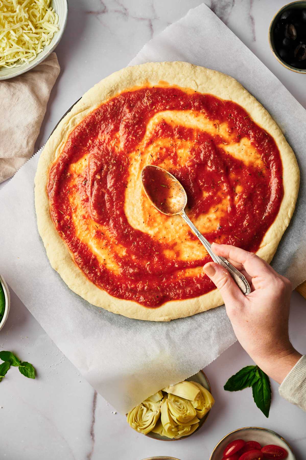 topping pizza dough with marinara sauce