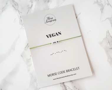 marble surface with a minimalist bracelet saying vegan in morse code