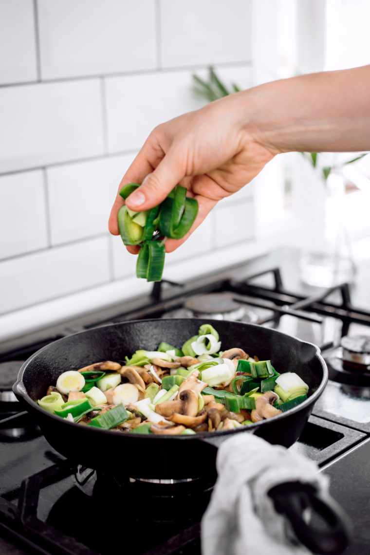 tossing leeks in a pan full of sauteed vegetables