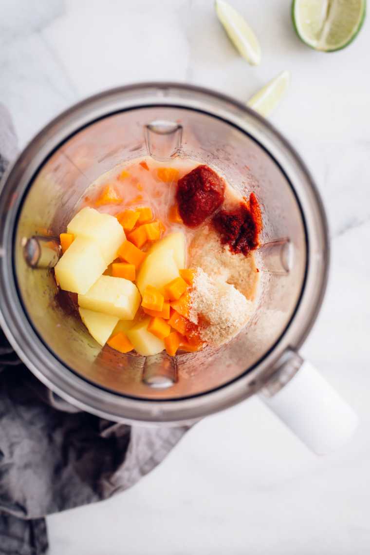 blender jar with potatoes, carrots, spices and tomato paste to make plant-based queso