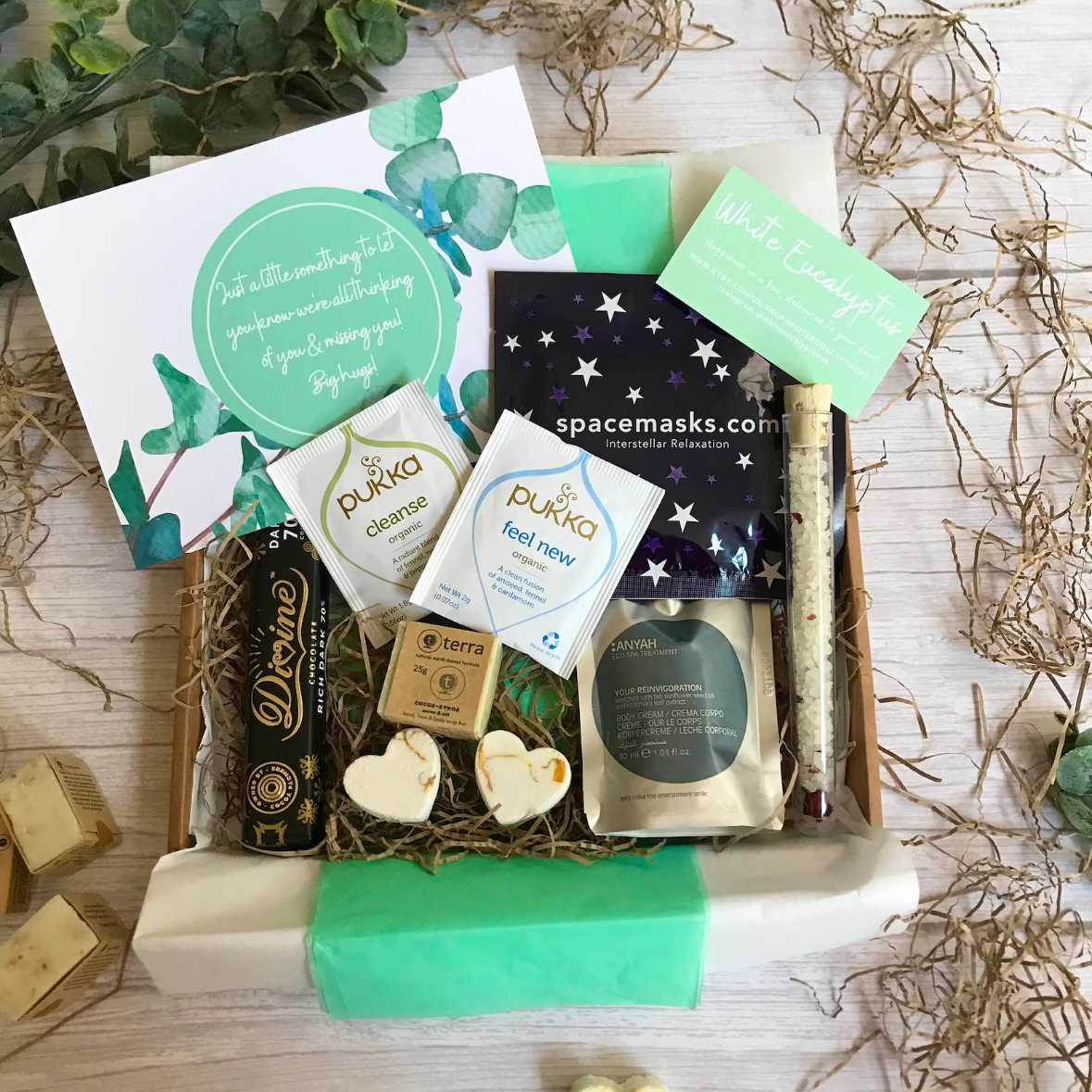 wooden table with a handmade vegan hamper filled with tea, soap and other wellness products
