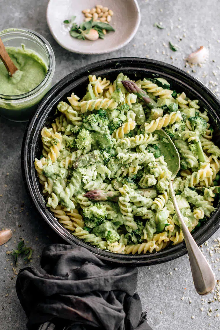 cooked pasta with bean pesto and broccoli in a black bowl