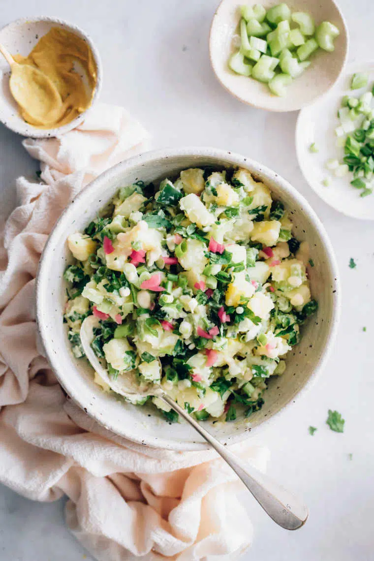 white bowl of dairy free potato salad standing on a white surface