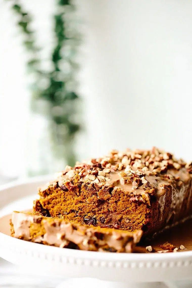 white plate with Vegan Pumpkin Cranberry Pecan Bread and one slice cut off