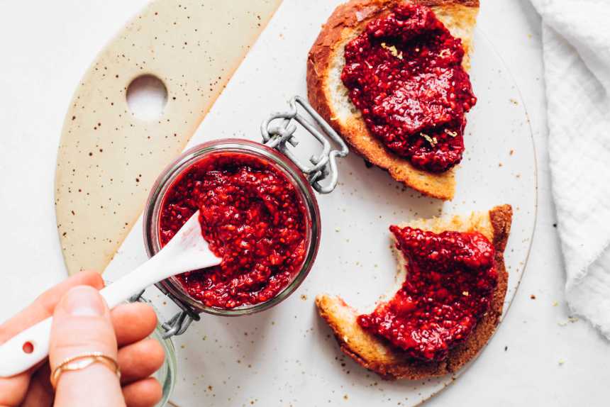 white chopping board with two slices of bread spread with sugar-free berry chia jam