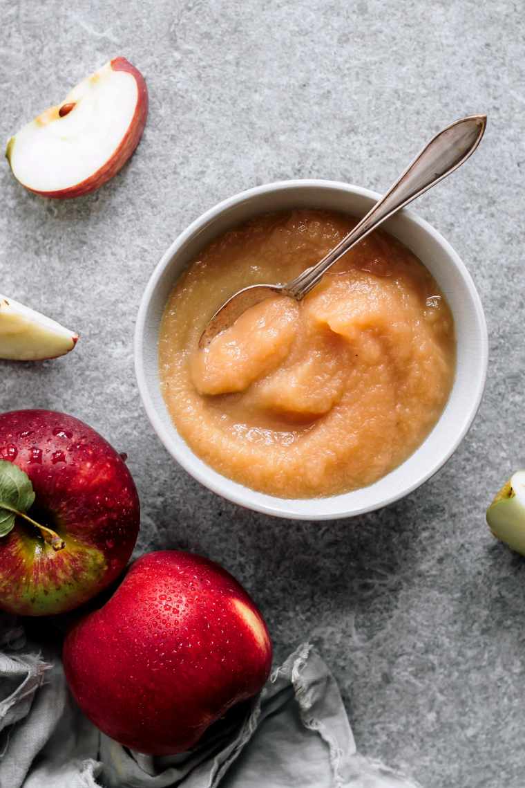 white bowl with apple sauce and a spoon on a table as one of the vegan food swaps for baking
