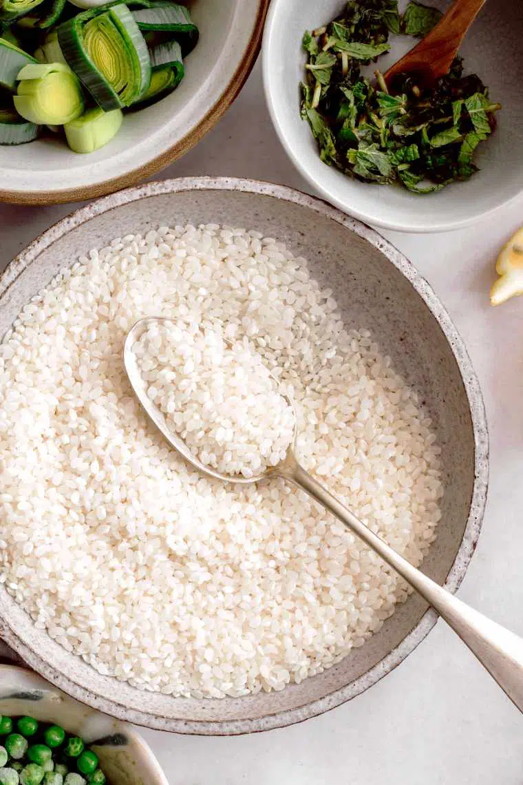 white rice and a spoon in a white bowl next to other vegan staple foods