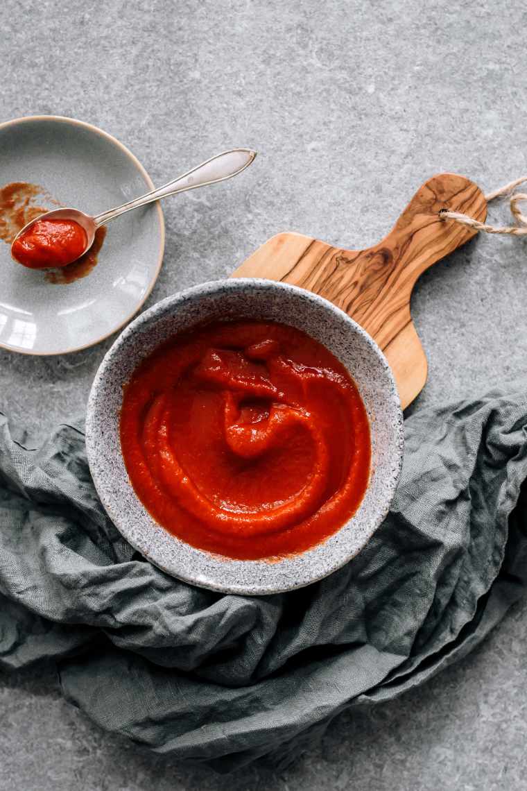 small bowl with tomato sauce on a wooden chopping board