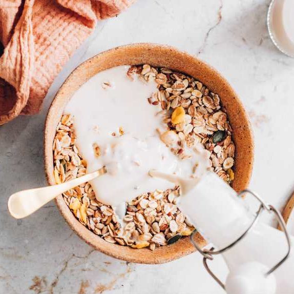 woman using plant based milk as one of many great vegan swaps in her muesli