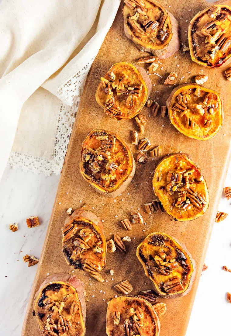 ten nicely arranged sweet potato rounds baked and glazed with maple syrup and topped with pecans