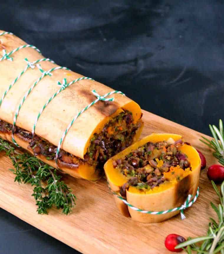 wooden chopping board with a vegan lentil stuffed butternut squash that was roasted in the oven for thanksgiving