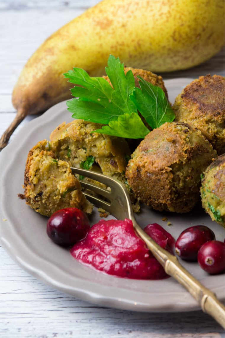 light brown plate with homemade vegan falafel, cranberry pear dip and some parsley next to a fork