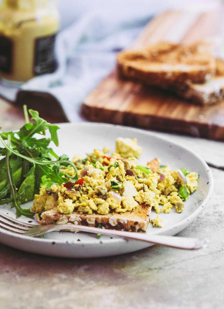 white plate with a slice of toast topped with tofu scramble