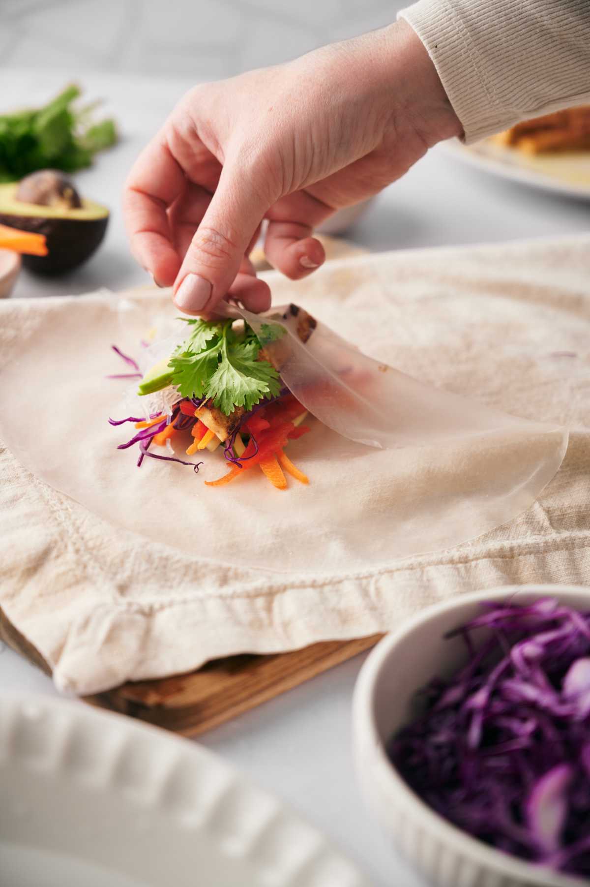 making summer rolls by folding rice paper sheet over filling