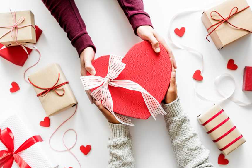 white table with two hands giving vegan Valentine's gifts to each other