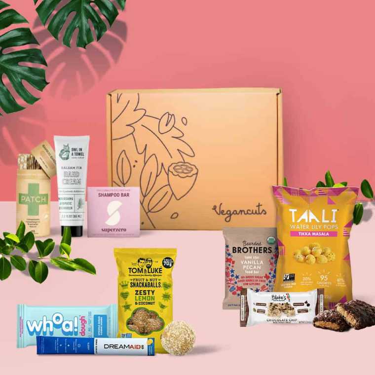 pink background with several vegan snacks and beauty items from the vegancuts box