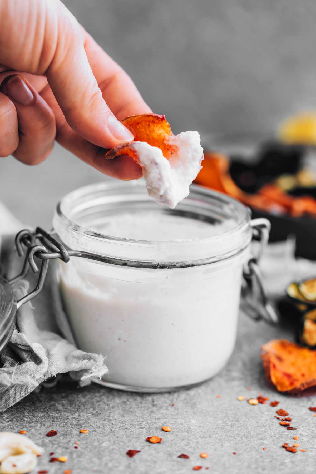 woman holing sweet potato chip and dipping it in vegan sour cream