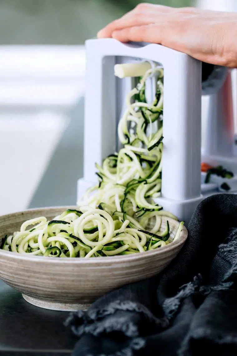 Woman using a spiralizer to turn a zucchini into noodle shape