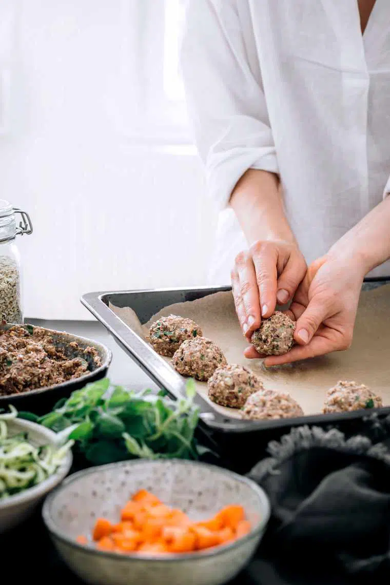 Woman forming vegan black bean meatballs with her hands and putting them on a baking sheet