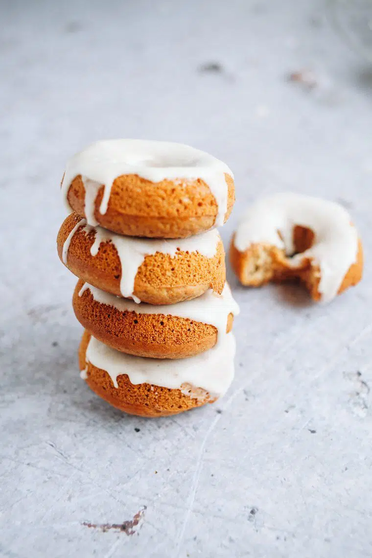 four small baked gingerbread doughnuts with a white glaze stacked on top of each other