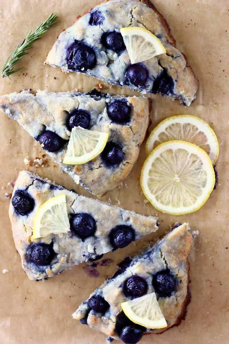 four pieces of gluten free vegan blueberry scones next to some slices of lemon