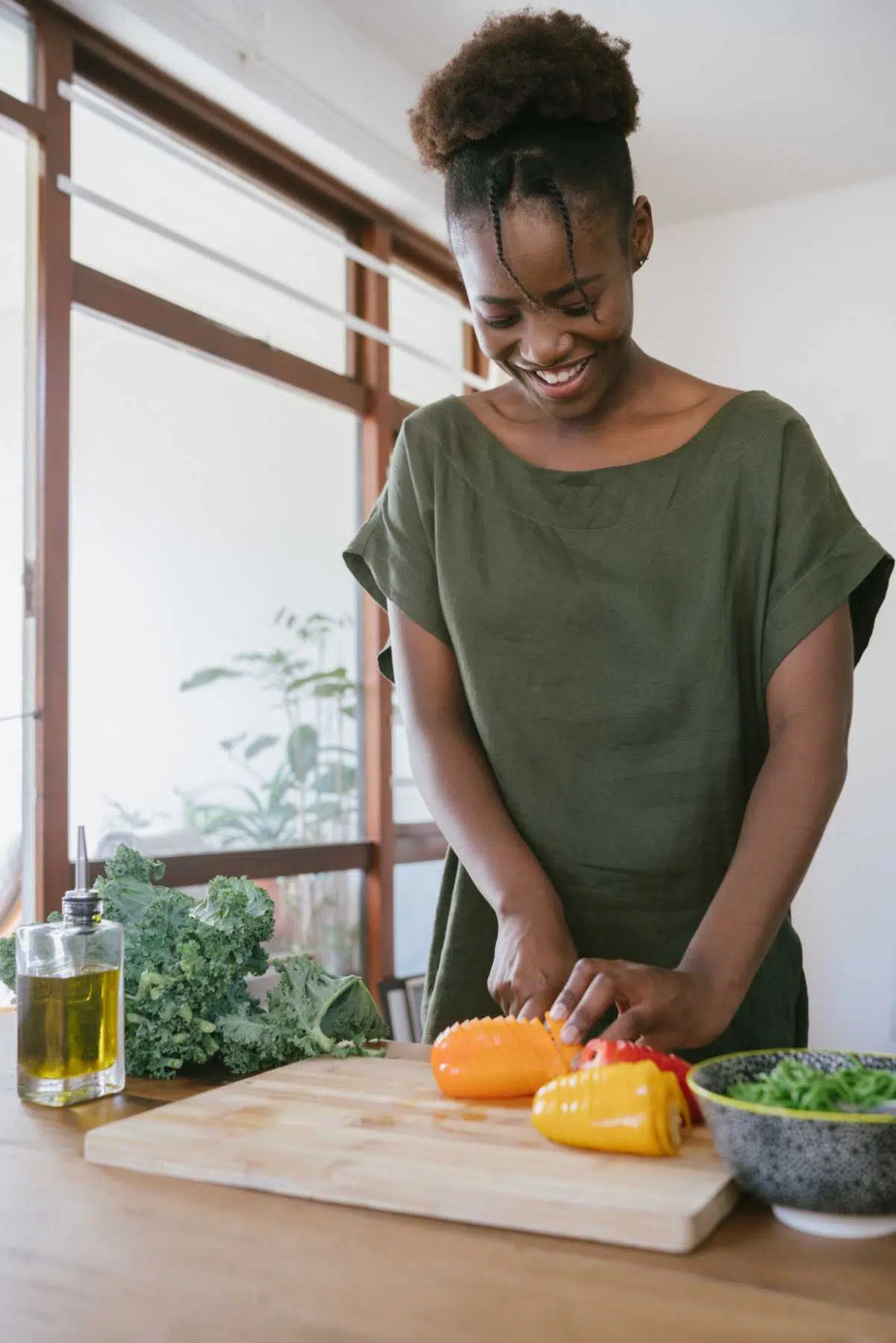 woman standing in the kitchen and chopping veggies while smiling