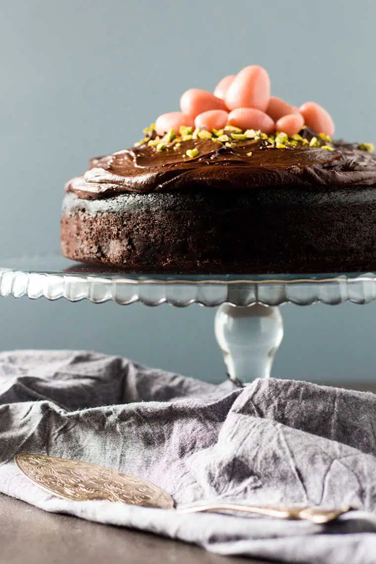 side view of a dark chocolate beetroot cake on a table topped with marzipan eggs