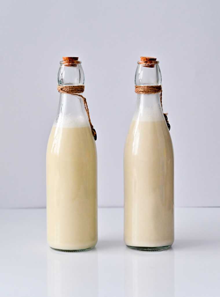 two bottles of milk on a white table