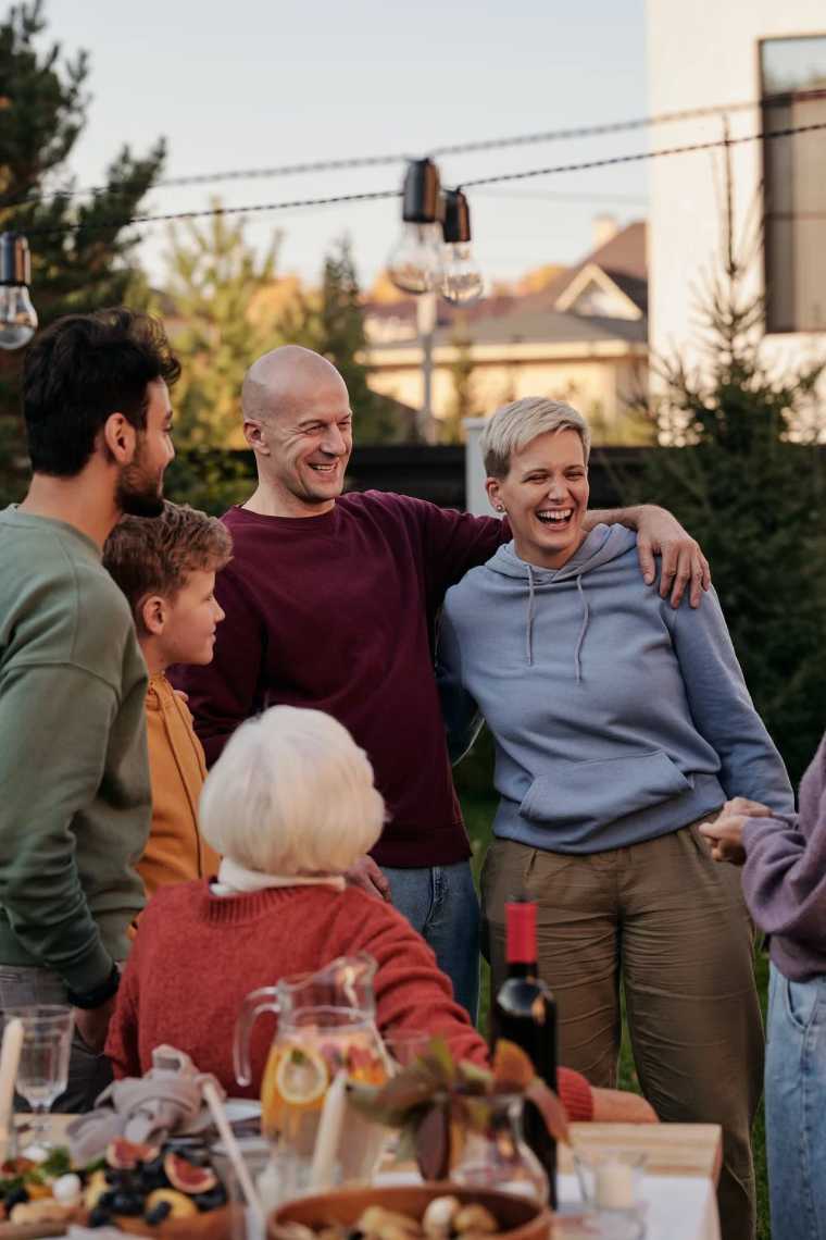 five people of different ages standing together in the backyard and laughing