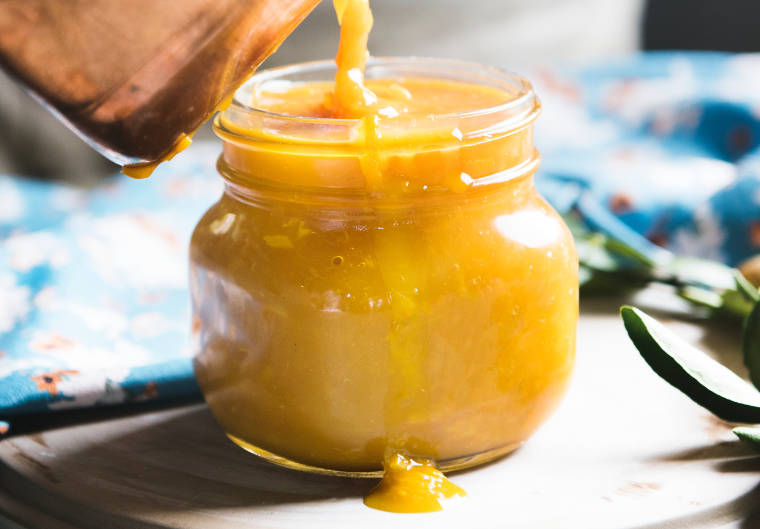Hand pouring apricot jam into a jar