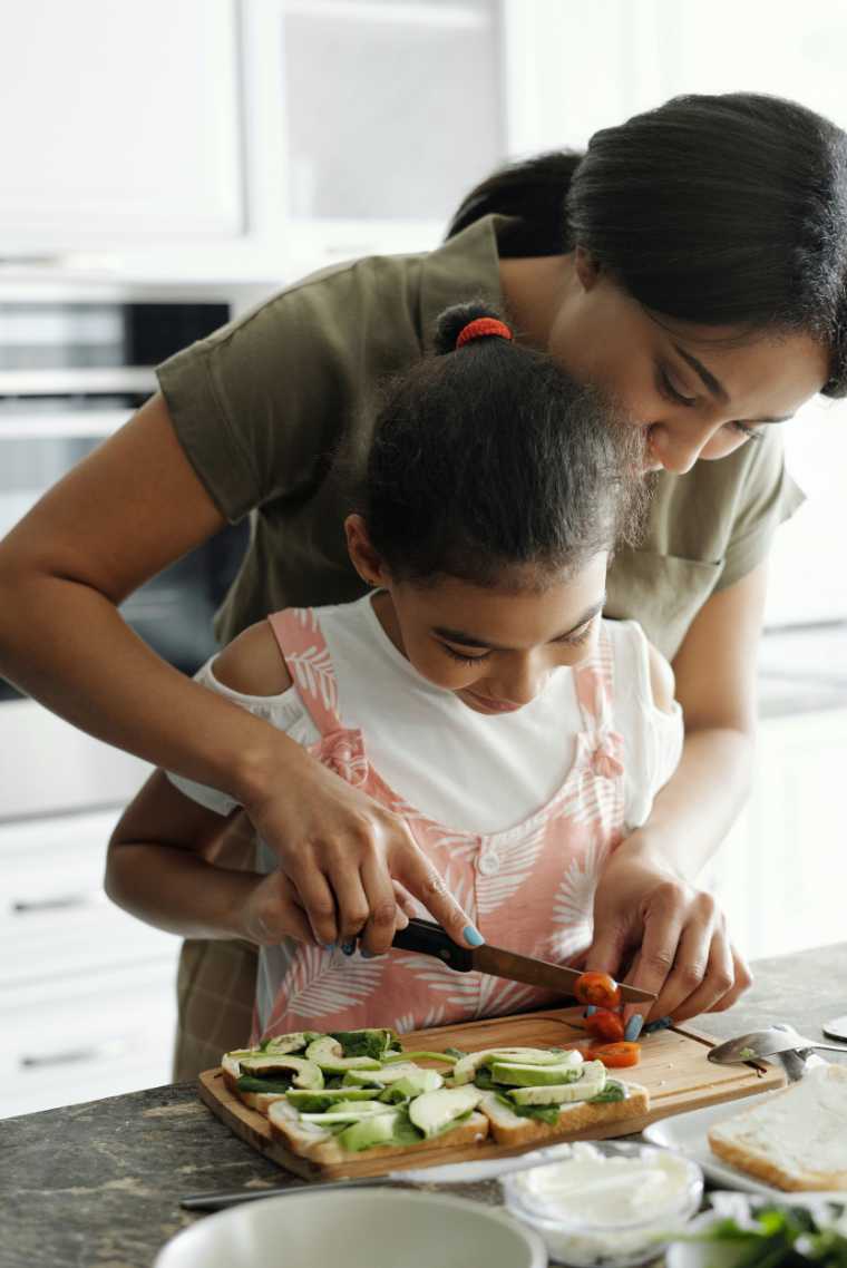 mother and daughter in kitchen cutting vegetables